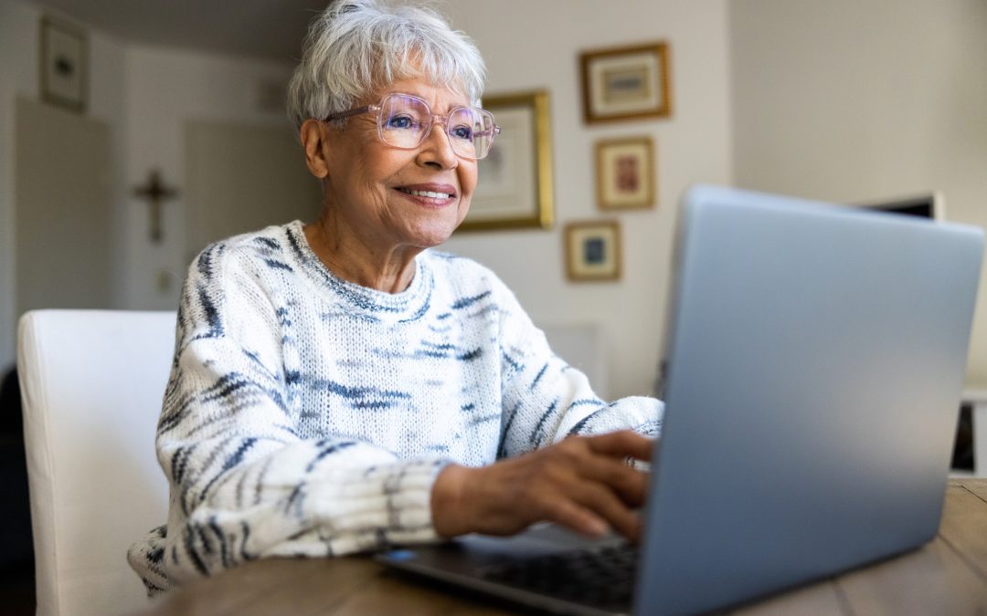 Older lady typing on laptop smiling